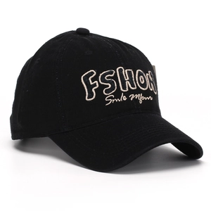 Close-up of black baseball cap featuring detailed beige embroidered letters and cotton texture