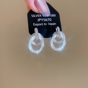 Dettaglio orecchini a cerchi intrecciati in argento 925 con zirconi su carta display
