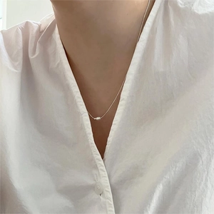 Close-up of a minimalist 925 sterling silver necklace with a single white pearl on a model