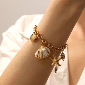 Detail of gold starfish and white seashell pendants on a pearl chain summer bracelet