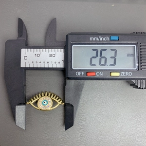 Digital caliper measuring the 26.3mm length of a gold evil eye pendant connector