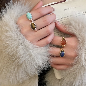 Detail of four retro oval stone rings in gold and silver plating on a soft fur background