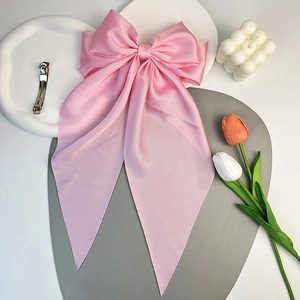 Dettaglio di un grande fiocco per capelli in raso rosa con tulipani e una candela