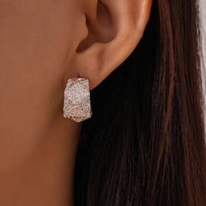 Macro shot of a minimalist silver geometric C-shape earring with irregular wrinkled texture