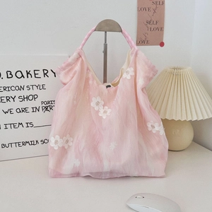 Detailed embroidery of white flowers on a pink tulle tote bag in a cozy lifestyle setting