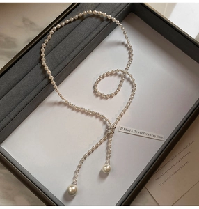 Detail of Y-shaped pearl necklace with zircon accents in a grey jewelry box display