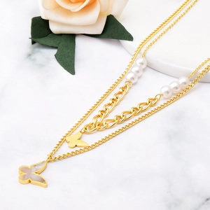 Double-layered gold necklace with pearl accents and shell butterfly pendant on marble