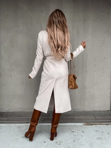Back view of long cream wool coat with waist tie and brown leather boots detail