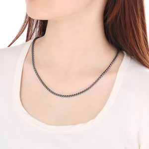 Close-up of a rainbow-colored woven metal necklace worn on model neck for fit