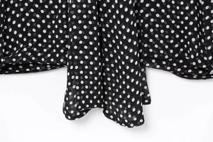 Detail of black chiffon cape blouse featuring white polka dots and neat hemline stitching