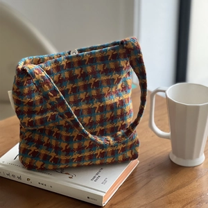 Retro plaid knit shoulder bag with blue and yellow patterns on book background