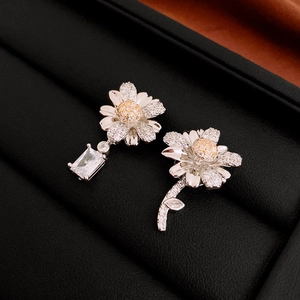 Macro shot of asymmetrical daisy earrings with white and yellow zircon in a black jewelry box