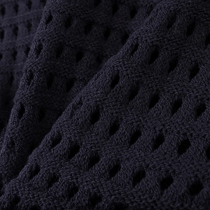 Close-up detail of dark blue hollow-out knit fabric with breathable mesh texture