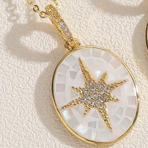 Makro-Detail des goldenen ovalen Anhängers mit Muschel-Inlay und Zirkonia-Sternen-Design