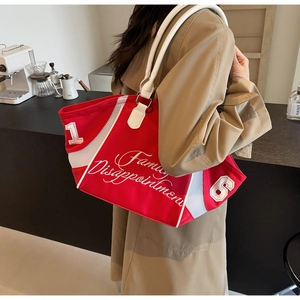 Detailed view of red canvas bowling bag with embroidered letters on a shoulder strap