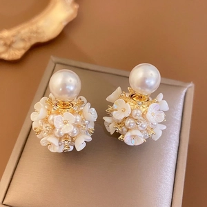 Boucles d'oreilles fleurs et perles dorées sur écrin de bijoux en velours champagne