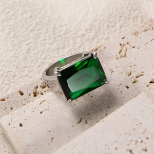 Macro detail of rectangle-cut emerald gemstone set in a silver-tone titanium steel band