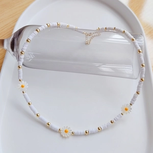Detailed shot of Bohemian daisy shell necklace with white clay discs and gold lobster clasp