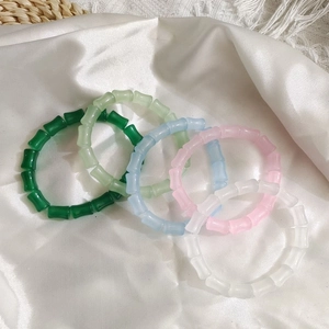 Detailed view of colorful bamboo-shaped bead bracelets on elegant white silk background