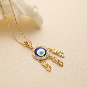 Collana dorata con malocchio blu e ciondoli a piuma in zircone su sfondo con conchiglia