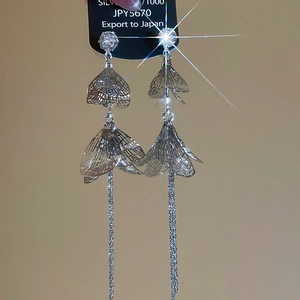 Gros plan de boucles d'oreilles pampilles pétales argent 1000 avec zircons cubiques et fond clair