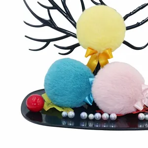 Close-up of soft plush powder puff balls with satin bows in yellow blue and pink