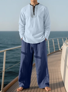 Men's linen vacation set detail featuring light blue shirt and dark blue pants on a boat deck