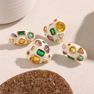 Détail macro de boucles d'oreilles ovales plaquées or 18K avec zircons colorés et émail blanc