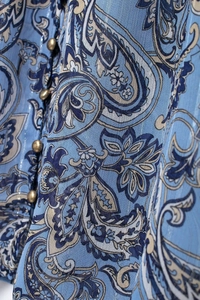 Macro del tessuto in chiffon paisley con eleganti bottoni a sfera dorati e dettagli
