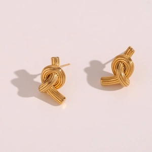 Detailed view of gold knotted stud earrings with a brushed metallic texture and finish