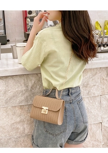 Close-up of brown wavy texture crossbody bag with gold metal lock and chain strap