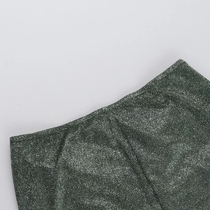 Detailed close-up of dark green glitter fabric texture and stitching on the dress