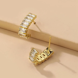 Macro view of gold geometric C-shaped earrings with rectangular baguette cubic zirconia