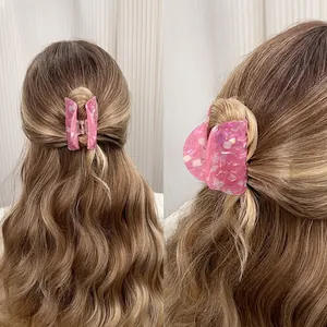 Colorful acetate claw clip with pink marble texture worn by a model in hair