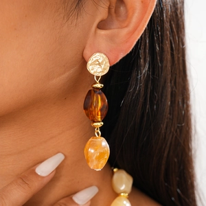 Close-up of vintage long drop earrings featuring amber acrylic beads and golden metal finish