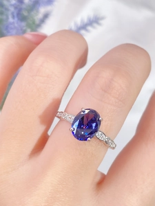 Close-up of 925 silver ring with large blue oval gemstone on a hand with flowers