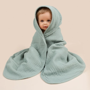 Macro detail of soft sage green cotton gauze fabric and hood texture on baby towel