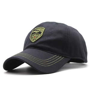 Detail of embroidered green shield patch on a black cotton twill baseball cap