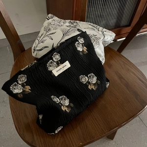 Close-up of retro jacquard makeup bags with floral embroidery on a dark wooden chair
