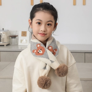 Détail d'une écharpe en tricot pour enfant avec motifs d'ours et pompons marrons