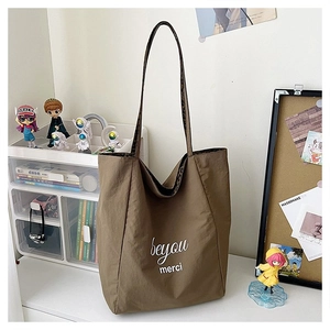 Detail of large brown tote bag with white lettering and leopard print shoulder strap