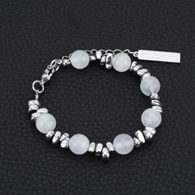 Close-up of faux pearl bracelet with silver spacers on a black leather background