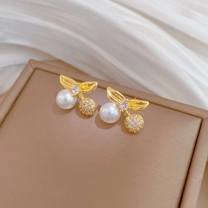 Macro shot of gold cherry earrings with white pearls and shimmering pave crystals