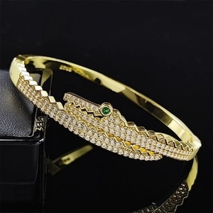 Macro shot of S925 sterling silver crocodile bracelet with white pavé stones and green eyes