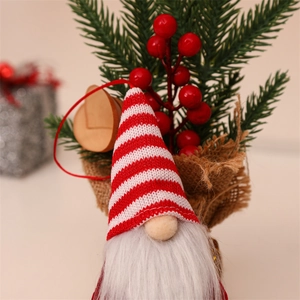 Close-up of knit Christmas gnome with white beard, red striped hat and festive decor