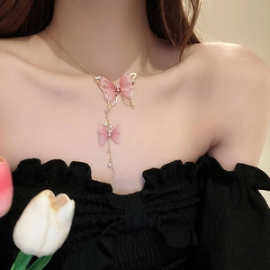 Detail view of pink tulle butterfly tassel necklace with pearls on a female model neck