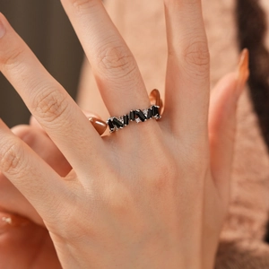 Detail view of irregular silver ring with baguette black stones on a hand