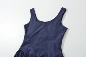 Detail of navy blue sleeveless dress featuring wide shoulder straps and pleated texture