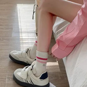 Close-up of pink striped smile socks and white platform sneakers on wooden floor