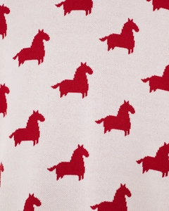 Vue rapprochée de la maille avec motifs de chevaux jacquard rouges sur pull crème